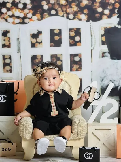 This little model is posing perfectly in her high-fashion themed photoshoot. It's a unique and playful concept for a sitter session.