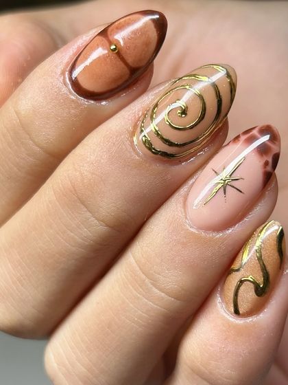 An incredible abstract nail art set in warm, earthy tones. This design features gold swirls, starbursts, and tortoise-shell-like patterns for a truly unique look.