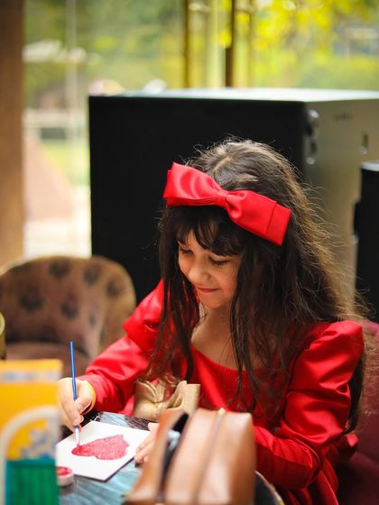 A young guest dressed in red enjoys a moment of quiet creativity, painting a heart. My brunches are designed to offer a variety of activities to suit every child's personality, from high-energy games to focused art sessions.