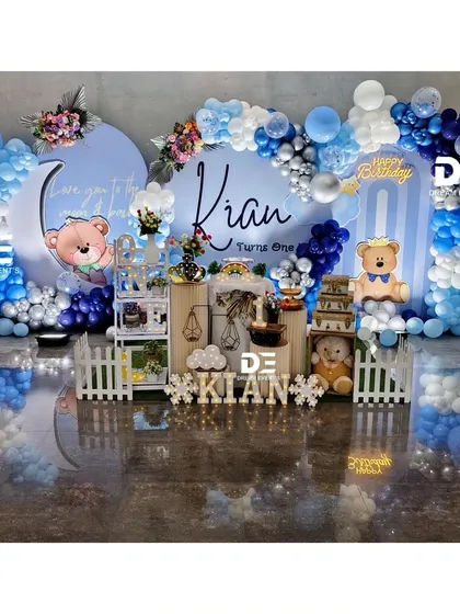 Here is a complete stage setup for a 'Love you to the moon and back' teddy bear theme. I used a beautiful blue and silver color palette, multiple backdrops, and charming props to create a dreamy and cohesive look for Kian's first birthday.