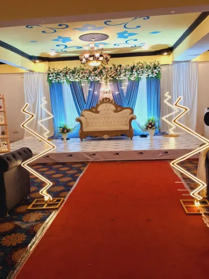 A wide-angle view showing how the stage design integrates with the entire hall. The red carpet aisle is lined with modern zig-zag LED lights that lead the eye directly to the beautifully decorated main stage.