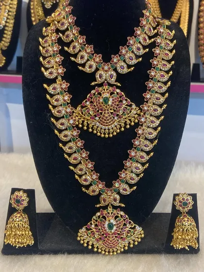 This layered mango haram set features intricate peacock pendants and is studded with kemp stones and white stones for extra sparkle.