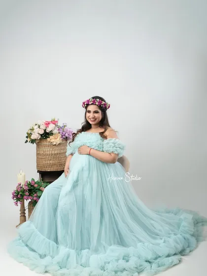 A classic, high-key studio portrait that emphasizes the beauty of the mother and her flowing gown. The simple background keeps all the focus on her radiant glow.
