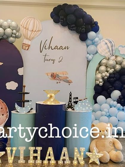 A vintage airplane and hot air balloon theme in shades of navy and light blue. This decoration includes arched backdrops, themed props, and a teddy bear pilot for a charming adventure in the sky.