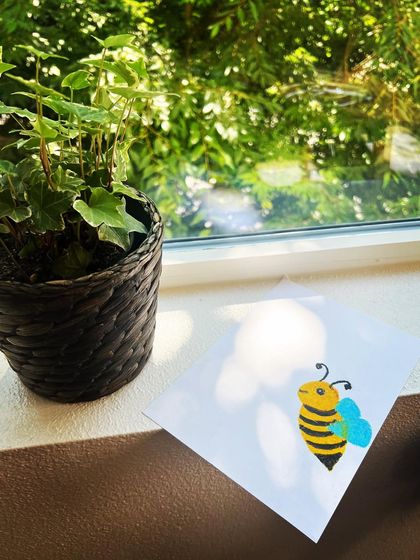 A cute little honey bee drawing from one of our online kids' classes, perfectly catching the sunlight by the window.
