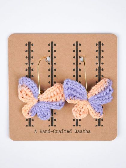 A product shot of the peach and lilac butterfly earrings, showing the delicate craftsmanship and beautiful color pairing.