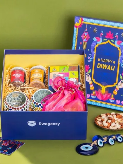 A styled shot of a Swageasy corporate Diwali hamper. The composition includes traditional festive elements like marigold flowers and diyas to create a warm, celebratory feel.