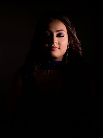 An artistic, low-light photo that creates a sense of mystery and drama. It shows how a strong makeup look can stand out even in shadow, perfect for evening events and photography.
