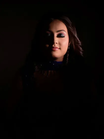 An artistic, low-light photo that creates a sense of mystery and drama. It shows how a strong makeup look can stand out even in shadow, perfect for evening events and photography.