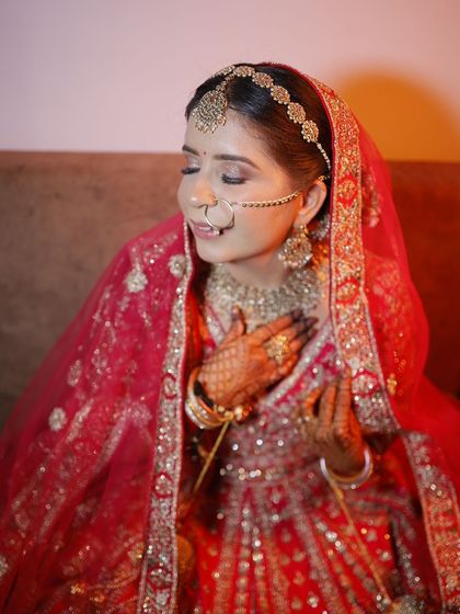 The perfect bridal pose. Her eyes are closed to show off the soft, blended eyeshadow, and her skin looks absolutely flawless in this classic red bridal attire.