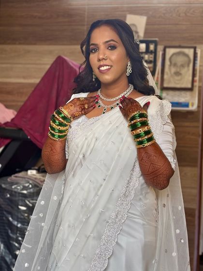 The bride is showing off her henna-adorned hands. Her hairstyle is soft and romantic, perfectly complementing her serene and happy expression.