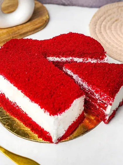 A stunning heart-shaped red velvet cake with a slice perfectly cut out, revealing the rich red layers and white cream cheese frosting. Styled on a bright, clean background, this image is ideal for bakery promotions and special occasions.