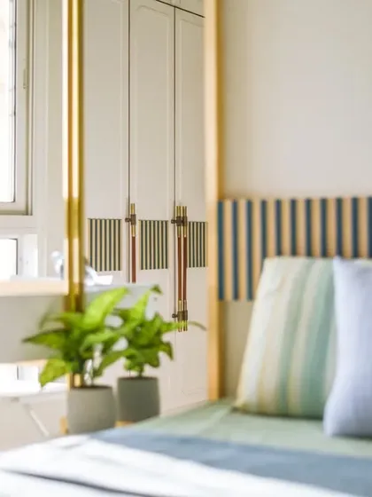 The guest bedroom features a custom headboard with striped fabric and a built-in bedside table. The brass light fixture adds a touch of warmth and elegance.
