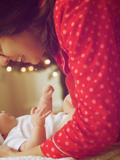 A heartwarming holiday-themed photo of a mother gazing lovingly at her newborn. The Santa hat adds a festive touch to this sweet, intimate moment.