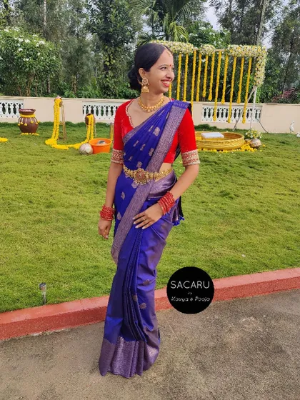 A full-length view of our client Thanni in her vibrant red velvet blouse and blue silk saree, a perfect example of contrast styling.
