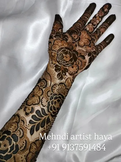 This is a classic example of a heavy bridal design, perfect for the main event. The artwork features a mix of large flowers and delicate, leafy vines that wrap around the hand and arm.