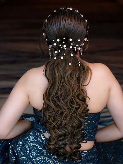 A beautiful open hairstyle for a reception or cocktail party. The hair is styled in soft curls and adorned with delicate pearl accessories.