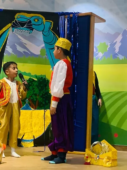 Two young actors engage in a scene from the Aladdin play, using microphones to project their voices.