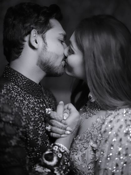 An intimate black and white photo capturing a kiss. This close-up shot focuses on the emotion and connection, with the monochrome edit adding a timeless and classic feel.