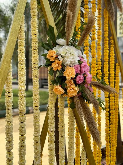 A close-up of the floral details on the triangular decor structures, combining delicate roses with traditional Indian flower strings.