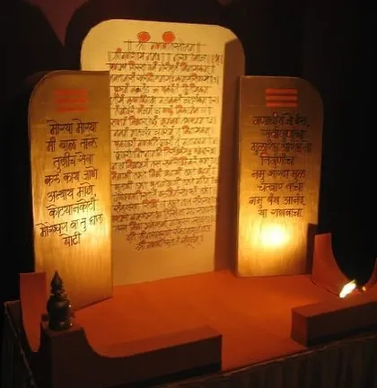 A custom-made throne for a Ganpati idol, designed to look like ancient scrolls with handwritten shlokas. The warm backlighting creates a divine glow, making it a unique and reverent centerpiece.