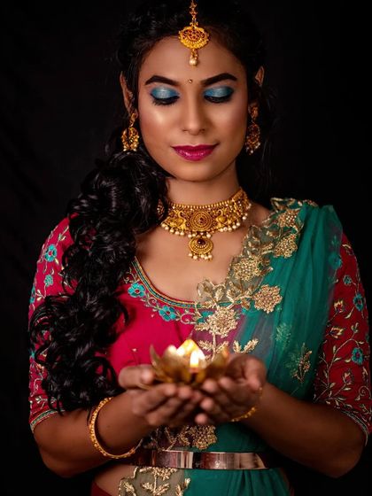 A beautiful shot with a diya, perfect for Diwali. The makeup is vibrant and designed to stand out against a dark background.