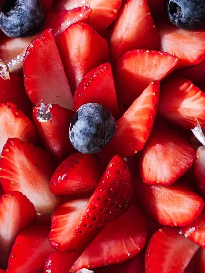 An extreme close-up macro shot of sliced strawberries and blueberries. This image focuses on the fresh, juicy texture of the fruit, making it a perfect supporting shot for any berry dessert.