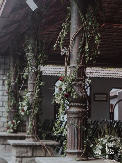 Wrought iron pillars at the venue are adorned with climbing vines and floral accents, enhancing the feeling of a timeless, romantic ruin.