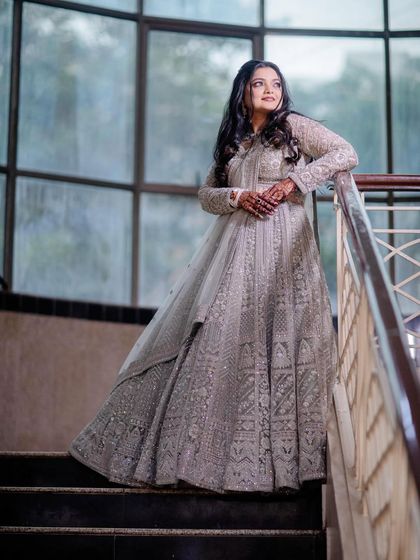 A client looking regal in a heavily embroidered silver-grey anarkali-style lehenga, perfect for a sangeet or reception.
