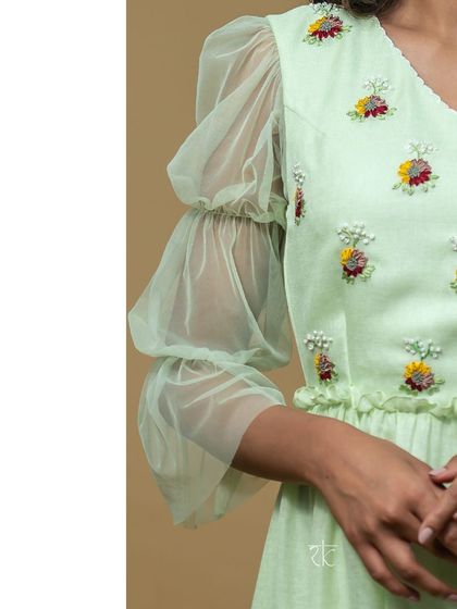 A close-up of the delicate floral embroidery on the bodice and the unique tiered puff sleeves made of sheer net.