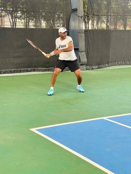 An adult player in a ready position, anticipating the opponent's next move. We teach strategic thinking and court awareness to players at all levels.