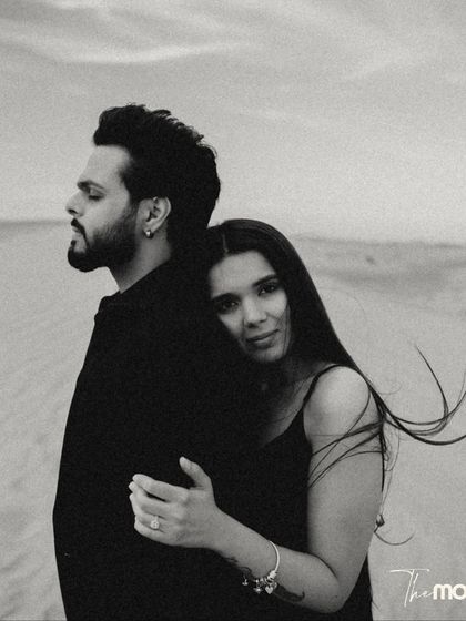 A beautiful black and white embrace in the desert. She rests her head on his back, looking at the camera with a gentle expression, creating a portrait that is both intimate and engaging.