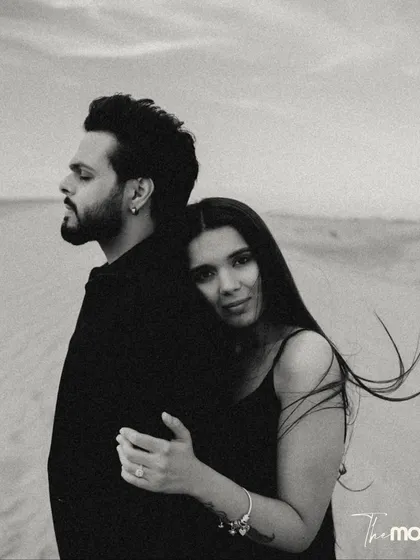 A beautiful black and white embrace in the desert. She rests her head on his back, looking at the camera with a gentle expression, creating a portrait that is both intimate and engaging.