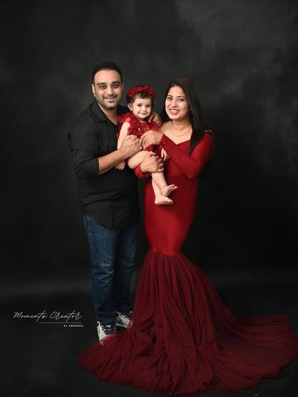 A classic family portrait against a dark, moody backdrop. The family's smiles light up the frame, showing that even in a formal setting, their warmth and love shine through.