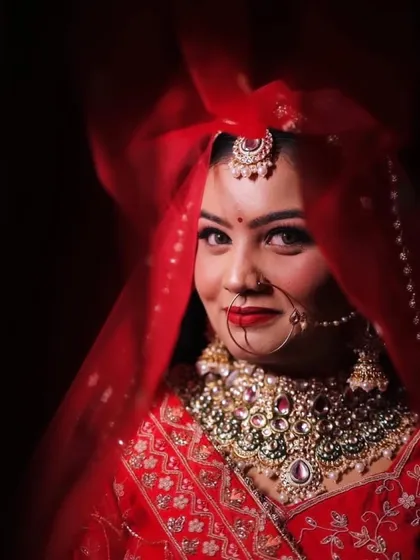 A close-up of Himanshi through her red veil. Her eyes and her beautiful smile shine through.