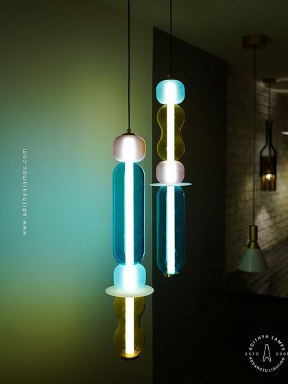 Add a playful pop of color with these kinetic sculpture pendants. Featuring stacked segments of hand-blown glass in teal, amber, and blush, these lights are a fun and artistic addition to any creative space.