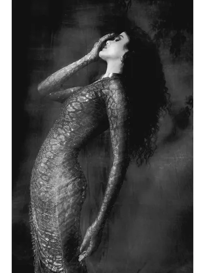 A key shot from the 'Judith' series. The model is styled in a form-fitting, snakeskin-textured gown by Itrh, her pose conveying a mix of anguish and power. The smoky, dark atmosphere is inspired by chiaroscuro painting.
