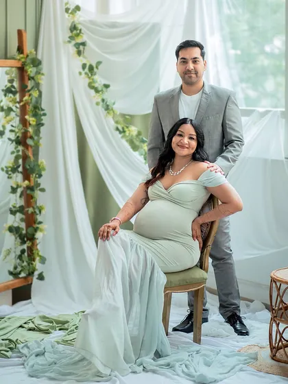 A formal yet loving portrait of the parents-to-be, framed by soft drapes and greenery in my studio.