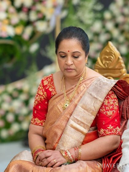 Our client Chandrakala, the mother of the bride, embodies grace in this vermilion red pure zari silk saree.