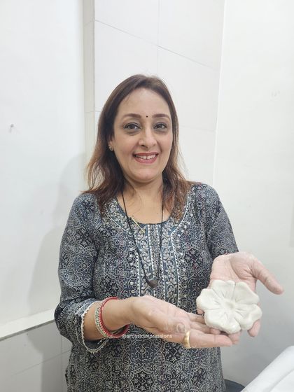 I am holding a freshly sculpted clay flower, one of many components for a larger heritage-inspired mural. Each piece is crafted by hand, ensuring that even within a repeating pattern, every element has a unique, personal touch.