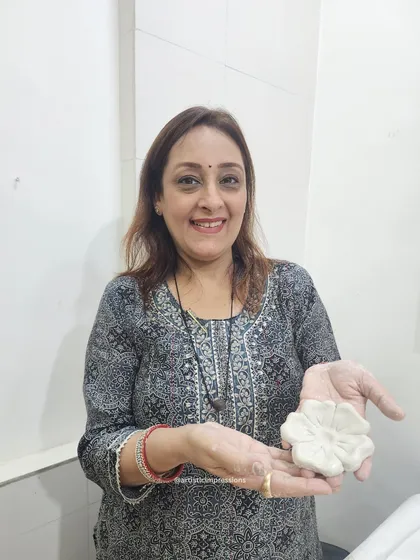 I love the tactile nature of my work. Here I am, holding a freshly sculpted clay flower, a small component that will become part of a much larger, intricate mural.