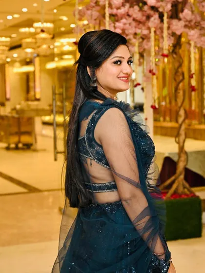 A side view of the client in the deep blue lehenga, showing off the back of her hairstyle and the sheer detailing of her outfit.