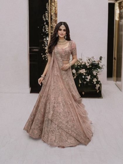 A full-length view of the dusty pink lehenga, showing how the pre-draped dupatta adds a modern and graceful touch to the traditional silhouette.