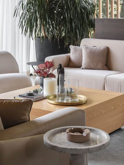 A close-up of the coffee table styling, where a simple brass tray and candle holders add a touch of elegance to the wooden table.