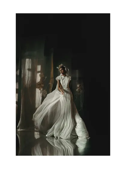 A wide shot from the Vaishali S. campaign, showing a flowing white gown with a mirrored floor. The reflection doubles the visual impact of the dress's movement and the dramatic, dark space.