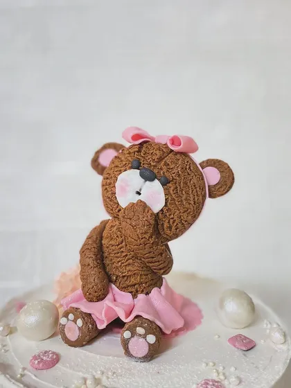 A close-up of the shy teddy bear topper, showing the texture and detail.