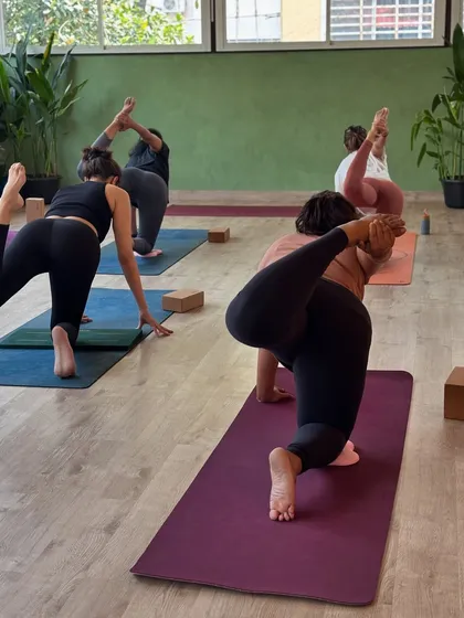 A dynamic group practicing a variation of tiger pose, showcasing balance, strength, and flexibility in motion.