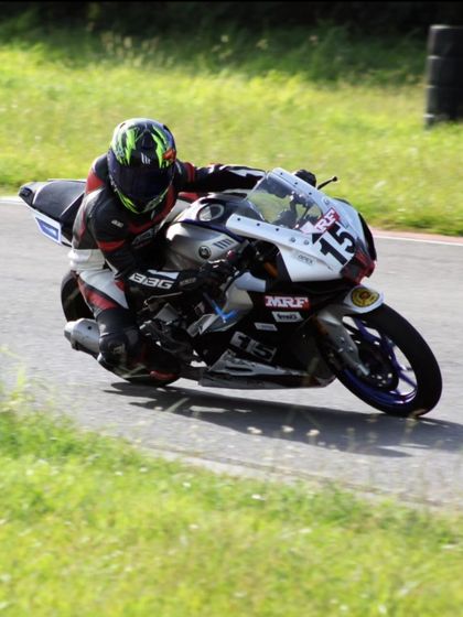 A rider on a number 15 Yamaha R15 shows great form while cornering during a race, fully focused on the track ahead.