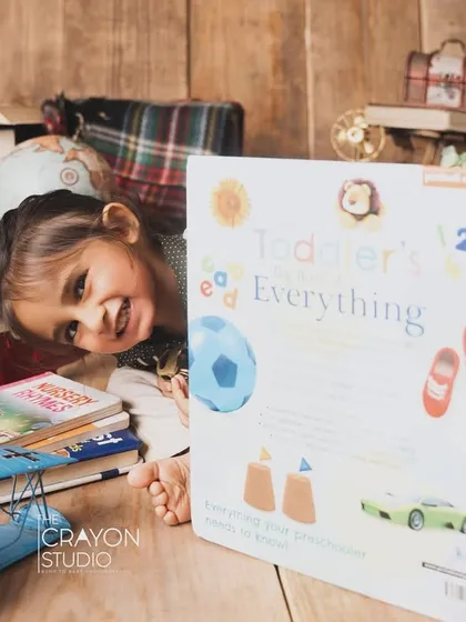 Peek-a-boo. A playful moment during the scholar-themed shoot, with the toddler hiding behind a giant book.