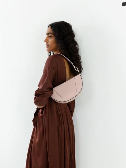 A profile shot of a model wearing a half-moon-shaped bag. This demonstrates how the bag sits on the body, providing important visual information for the customer.